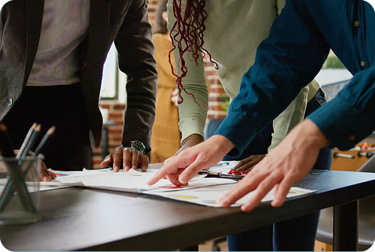 Diverse team of coworkers looking at business charts on documents, analyzing research information and statistics on diagrams review. People using papers with infographics data report. Close up.